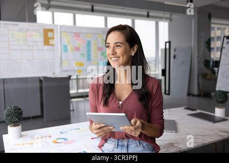 Happy professional woman standing in office with tablet Stock Photo