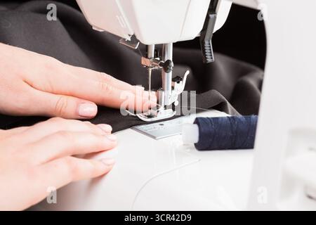 Sewing machine in action with hands guiding fabric during a creative crafting session Stock Photo