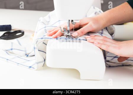 Sewing fabric with a sewing machine in a bright workspace during daytime Stock Photo