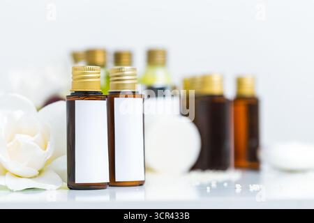 Assorted essential oil bottles displayed on a shelf with white flowers in a wellness setting Stock Photo