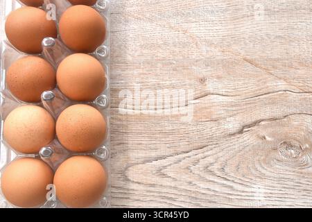 brown raw eggshell arranging in transparent plastic packing on wooden table Stock Photo