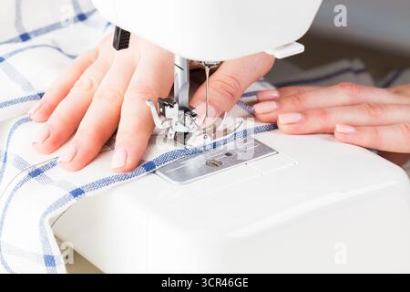 Sewing fabric on a sewing machine in a well-lit workspace during daylight hours Stock Photo