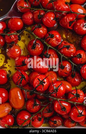 Close-up of roasted cherry tomatoes on the vine in olive oil. Stock Photo