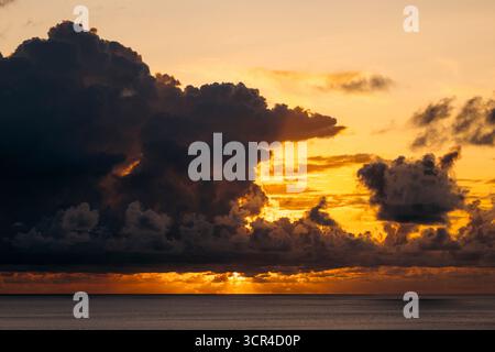 A vibrant sunset with dramatic clouds over a calm ocean horizon. Paya, on We Island in Aceh, Sumatra, Indonesia Stock Photo