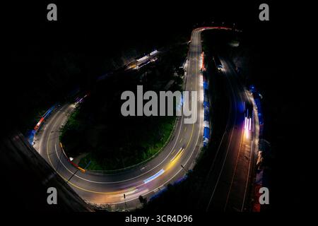 Light trails on a curving road at night, surrounded by darkness and illuminated barriers. Kelok 9, or the 9 hairpins, a big viaduct with 9 big curves in Harau, West Sumatra, Sumatra, Indonesia Stock Photo