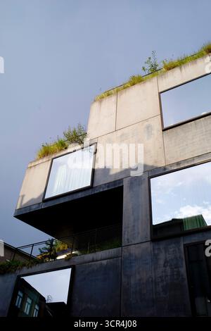 Modern concrete building with large reflective windows and rooftop greenery under a blue sky. Brussels, Belgium Stock Photo