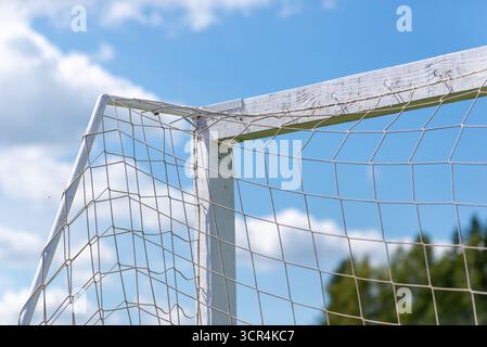 Close-up of white wooden football goal with attached net against clear blue sky. Stock Photo