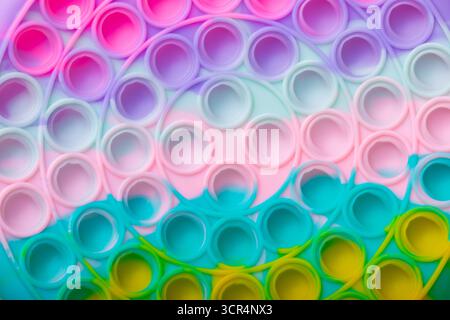 Close-up of a vibrant, rainbow-colored silicone pop it fidget toy, showcasing bright pastel circles and playful textures, perfect for backgrounds or c Stock Photo