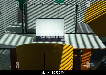 Laptop Workspace Shadows Light Interior office space Creative modern office scene with open laptop on shared desk, dramatic sunlight filtering through Stock Photo