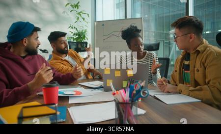 Happy smiling successful multiethnic informal casual office business team research corporate project checking data in paper laptop whiteboard graphic Stock Photo