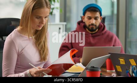 Concentrated busy informal teamwork in office startup business at table three multinational colleagues Asian male with digital tablet African woman Stock Photo