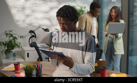 Concentrated African American business man pondering writing notes businessman male guy working in informal creative startup office near diversity Stock Photo