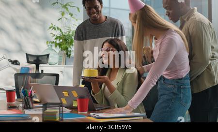 Indian businesswoman Arabian woman working laptop in office three multiracial business colleagues make surprise celebrating congratulate with birthday Stock Photo