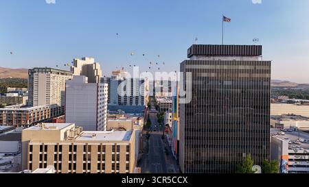 Aerial view of buildings casting long shadows as hot air balloons float above the city streets, Reno, Nevada, United States. Stock Photo