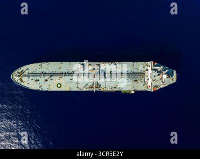 Aerial view of a tanker ship cutting through the deep blue sea, a stark contrast against the ship's pale deck, Piraeus, Greece. Stock Photo