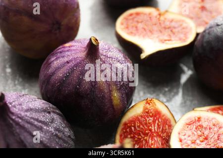 Whole and cut figs on gray table, closeup Stock Photo