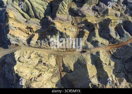 Aerial view of textured, undulating landscape of Huoyun Valley painted in earthy tones with winding roads cutting through the terrain, Huoyun Valley, China. Stock Photo