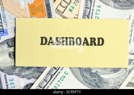 DASHBOARD word written on yellow paper on the background of banknotes. Analyst working with Financial Report and Business Analytics concept. Stock Photo