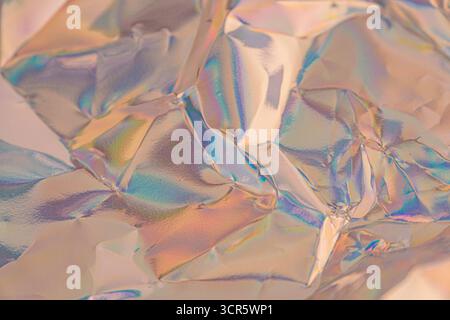 An abstract, iridescent textured surface resembling shattered glass or metallic glint, transitioning from warm to cool hues, suitable for luxury, frag Stock Photo