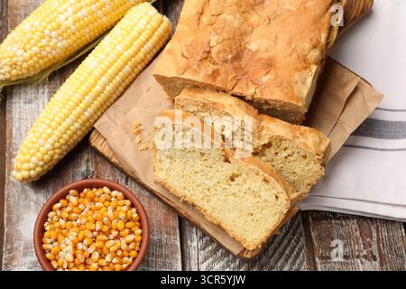 Freshly baked cut cornbread, cobs and seeds on wooden table, flat lay Stock Photo