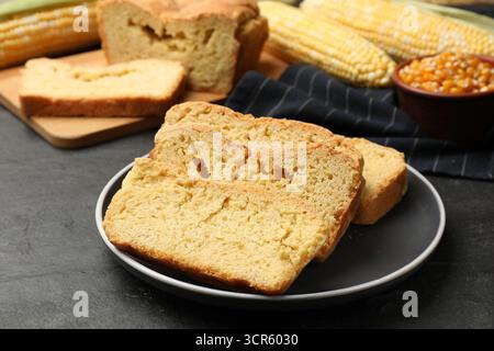 Freshly baked cornbread, cobs and seeds on black table, closeup Stock Photo