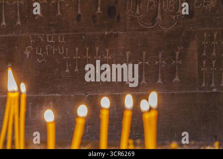 View of flickering candlelight dances against the ancient stone, illuminating carved crosses and Armenian script, creating a warm glow in Noravank Monastery, Vayots Dzor Province, Armenia. Stock Photo