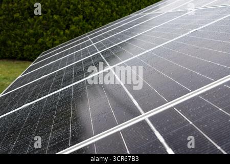 Close-up macro view of solar panel surface with raindrops on the glass cells, symbolizing clean energy and nature. Stock Photo