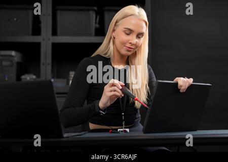 Young blonde IT technician repairing a laptop in a server room during maintenance and diagnostics Stock Photo