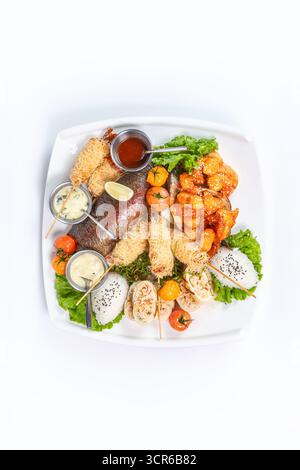Grilled fish, spicy shrimp, spring rolls, and rice on white plate. Top view - perfect for menus, food photography, and advertising. Stock Photo