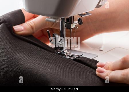 Sewing machine in use for crafting clothing with precision and care during daylight hours Stock Photo