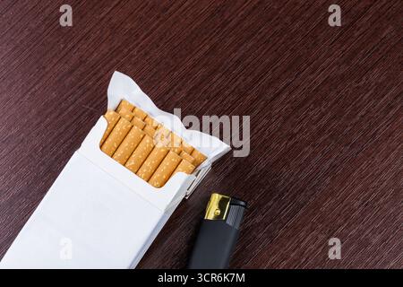 Cigarette pack and lighter resting on a wooden surface in a calm indoor setting Stock Photo
