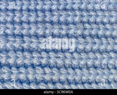 A macro view of blue knitted fabric showcasing the texture and thick yarn weave. The soft fibers of cozy and durable material. Stock Photo