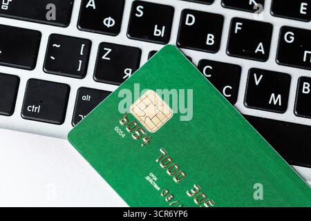 Close-up of a green credit card on a laptop keyboard during a payment process Stock Photo
