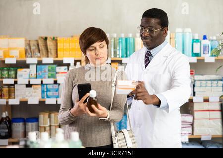Woman buyer scans syrup qr code with man pharmacist Stock Photo