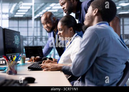 Developer works together with colleagues in server farm, using artificial intelligence tech for increased productivity. Teamworking data center employees collaborating to implement AI driven solutions Stock Photo