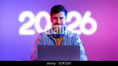 Programmer Working at Desk in Neon Studio With Laptop and Headphones Stock Photo