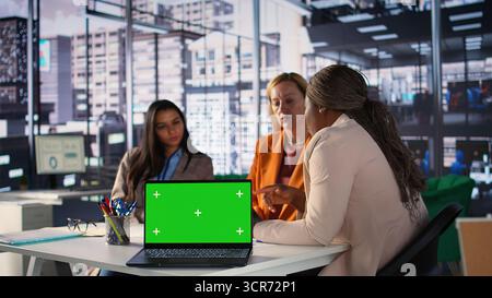 Multicultural team of specialists using mockup copy space in the office, working with resilience to accomplish enterprise objectives. Manager and employees meeting for a briefing. Camera B. Stock Photo