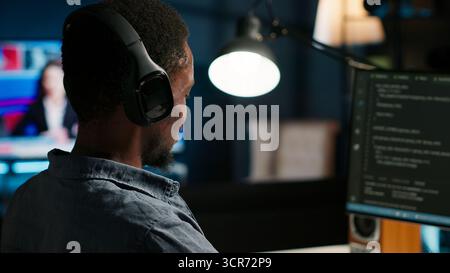 Male developer entering binary data on terminal panel while writing html code. Software engineer working on troubleshooting with programming language, internet and server security. Camera B. Stock Photo