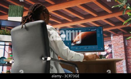 Woman at home using generative artificial intelligence website generating videos using diffusion models. Person drinking coffee and using AI virtual assistant producing clips, camera B Stock Photo
