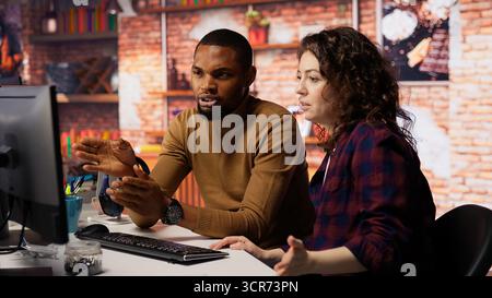Engineers cooperating in startup office, using programming languages on PC to build applications. Coworkers doing brainstorming, using computer in software development agency to code, camera B Stock Photo