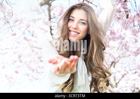young woman with a beaming smile offers her hand Stock Photo