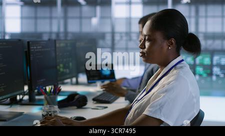 Computer scientists in data center implementing AI predictive maintenance systems. Server farm employees using artificial intelligence to identify hardware failures impacting operations, camera A Stock Photo