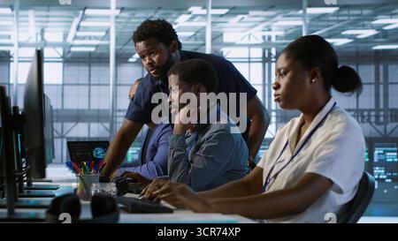 Manager supervising server room workers developing disaster recovery plans ensuring minimal downtime. Supervisor oversees data center technicians using data analytics to monitor performance, camera A Stock Photo