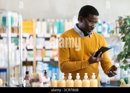African American man checking syrup medicine details on smartphone Stock Photo