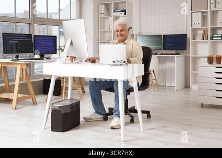 Senior programmer working at table in office Stock Photo