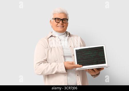 Senior programmer with laptop on light background Stock Photo