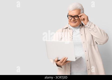 Senior programmer with laptop on light background Stock Photo