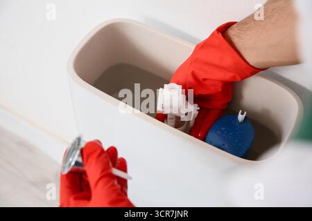 Male plumber repairing toilet in restroom, closeup Stock Photo