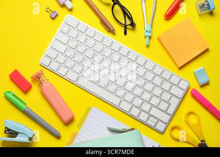 Composition with modern computer keyboard and different stationery on yellow background Stock Photo