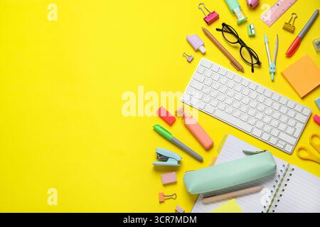 Composition with modern computer keyboard, glasses and different stationery on yellow background Stock Photo